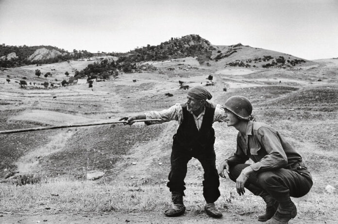 ITALY_Near Troina_1943_Sicilian peasant telling an American officer which way the Germans had gone_Robert Capa